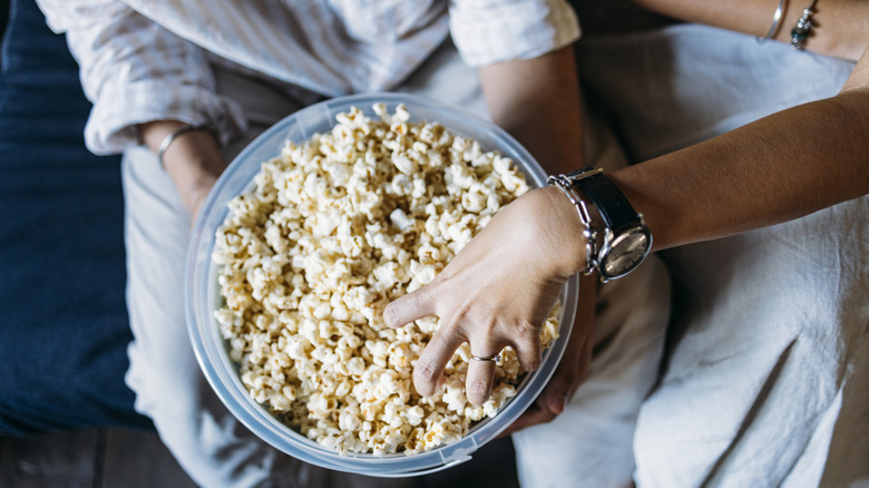 Two people sitting together enjoying a bowl of popcorn