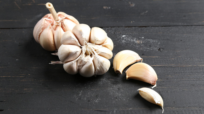 Two bulbs of garlic with three cloves on a black table