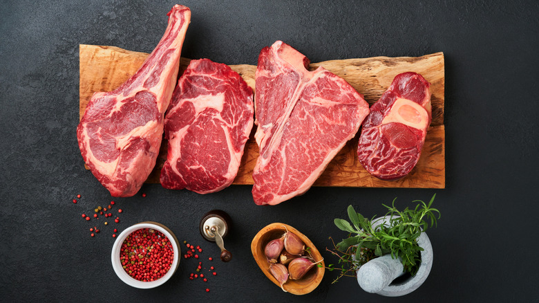 Raw steak cuts on a wooden board with herbs and spices