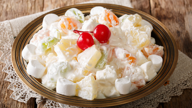 a plate of ambrosia salad topped with maraschino cherries