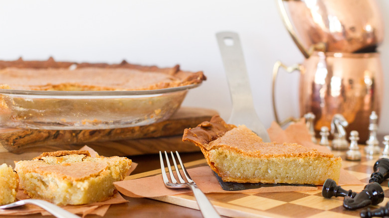 slice of chess pie on a chessboard with remainder of whole pie in background
