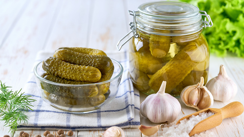 Homemade canned dill pickles with raw garlic, salt, and dill on the table