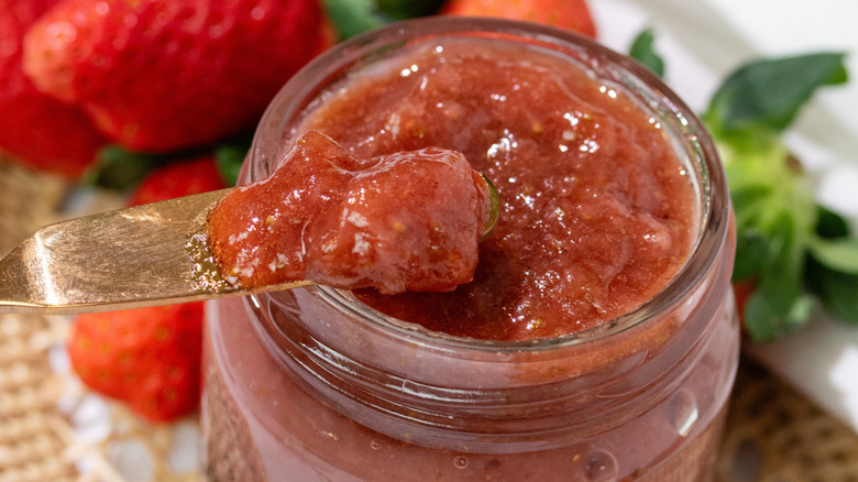 Homemade strawberry jam next to some fresh strawberries