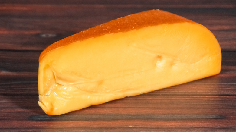 A wedge of smoked Gouda cheese on a wooden table