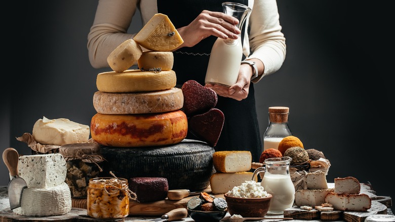 cheeses on a table and person holding milk