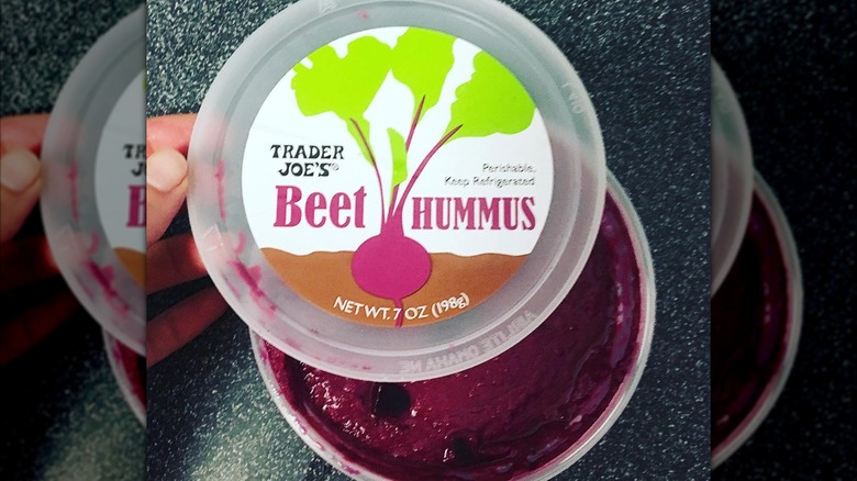 hand holding an opened container of Trader Joe's beet hummus