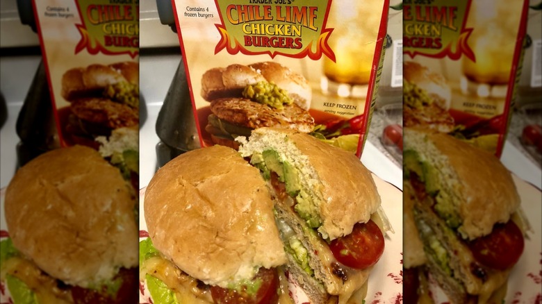 Trader Joe's chile lime chicken burger prepared on a bun with toppings, the box in the background