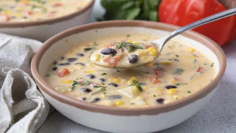 Bowl of corn chowder with spoonful being lifted out of it
