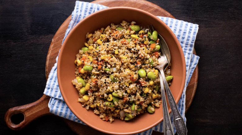 Bowl of Fried Brown Rice on wooden board and striped dish cloth