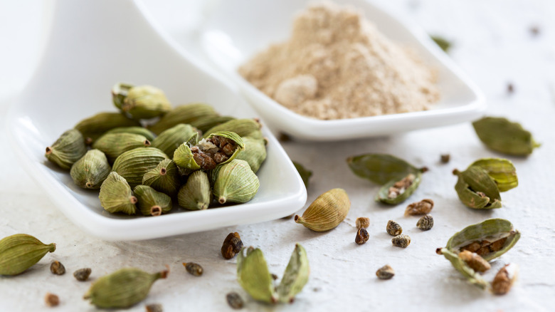 Both ground and whole cardamom in small white dishes