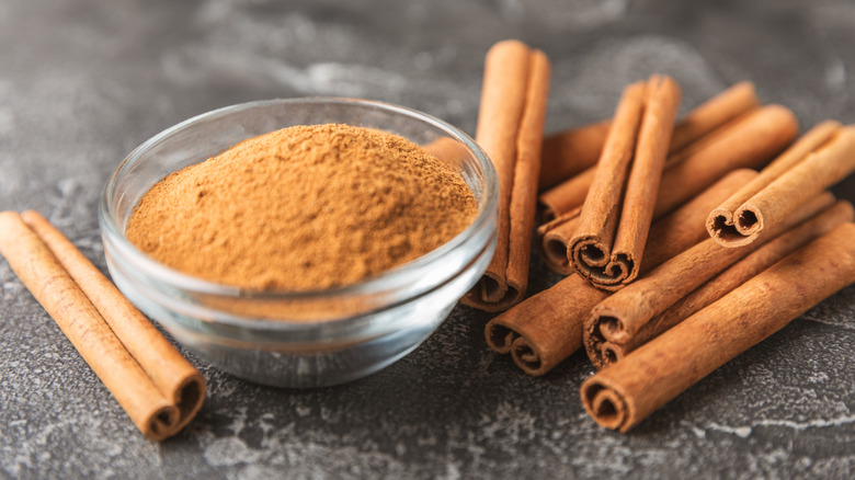 Closeup of bowl of ground cinnamon and cinnamon sticks