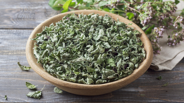 Dried oregano in a bowl on a wooden table
