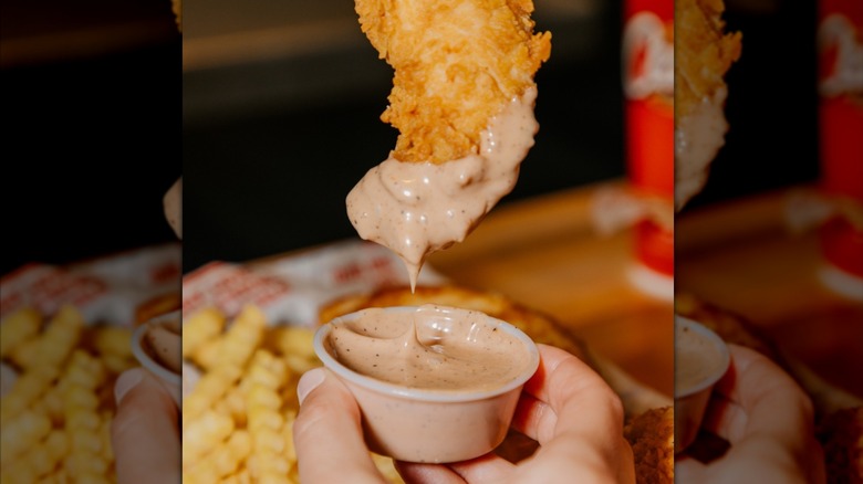 chicken strip dipped in Canes sauce