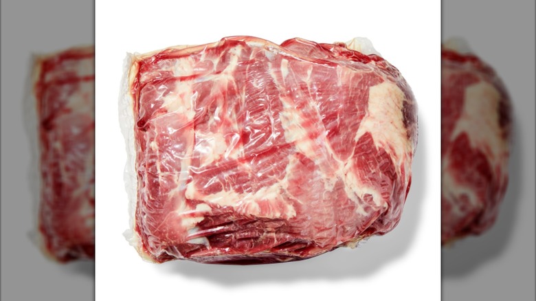 Plastic wrapped bone-in pork shoulder butt.