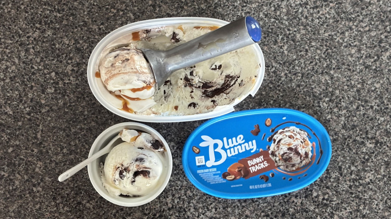 top-down view of ice cream scoop in carton of ice cream with bowl of ice cream beside it