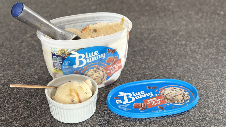 ice cream with caramel ribbon scooped out of container and into white bowl