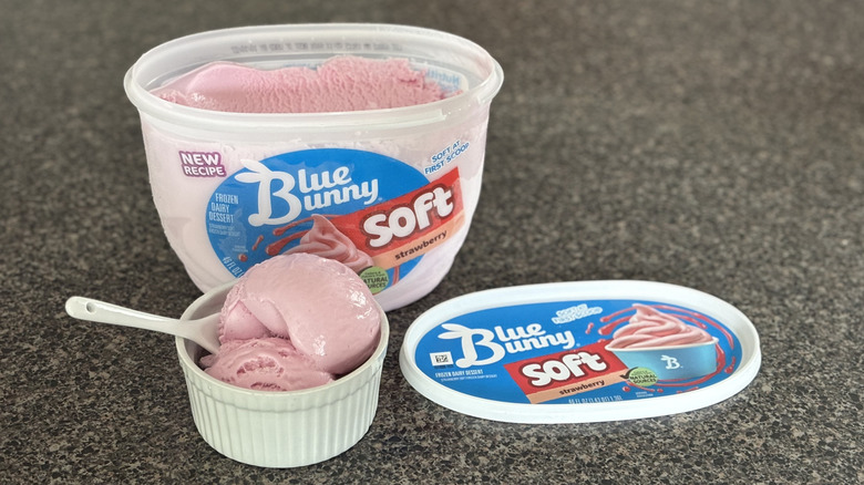 bowl of soft serve strawberry ice cream with carton in the background