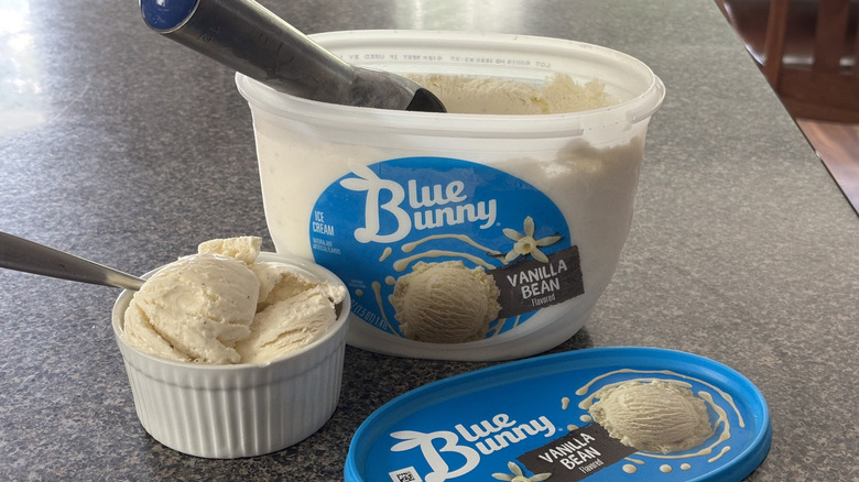 container of vanilla bean ice cream with bowl of vanilla scoops in front