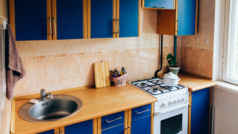 Retro kitchen with wood counters, blue cupboards, and a peach backsplash