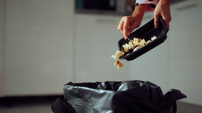 Throwing out leftovers into trash can