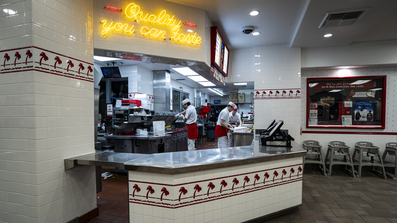 Workers inside an In-N-Out location preparing food in the kitchen.