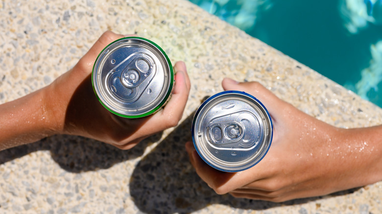 holding canned cocktails by pool