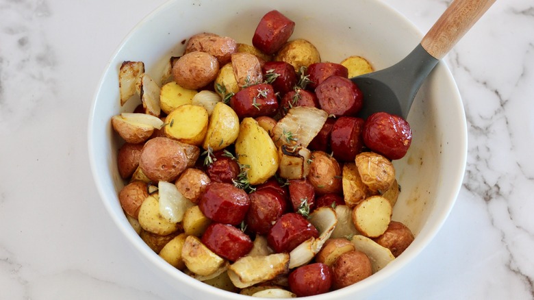 White serving bowl filled with cooked sausage and potatoes