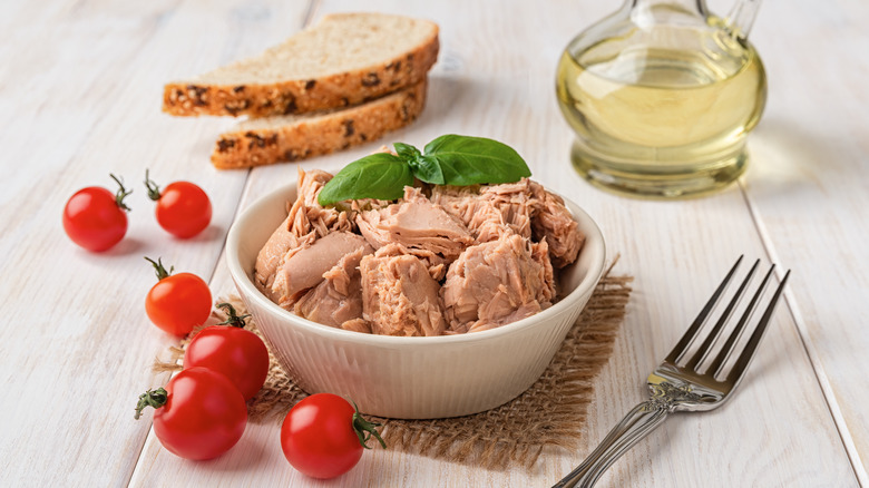Canned tuna in a bowl with olive oil, bread, and tomatoes
