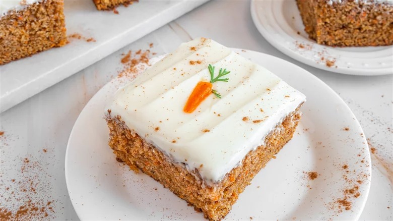 Slice of carrot sheet cake with mini carrot decoration