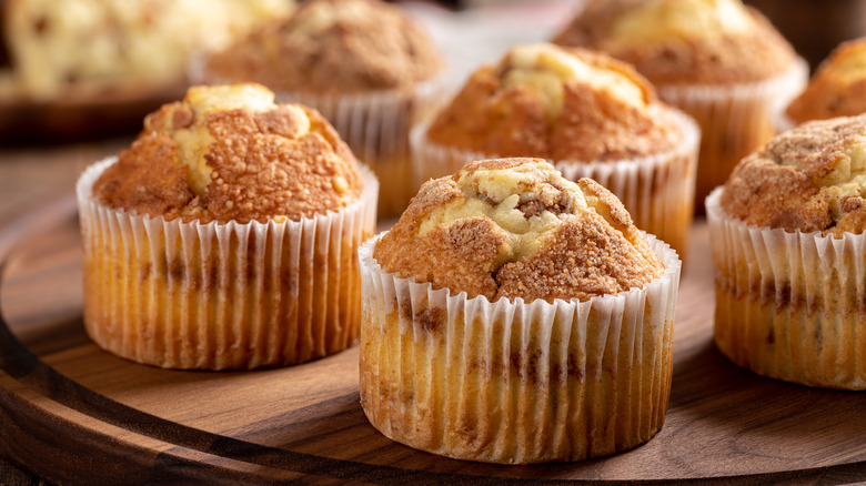 Baked muffins in paper liners on wooden board.