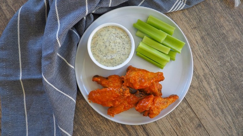 aerial shot of copycat Buffalo Wild Wings with celery and a dipping sauce, all on a white plate