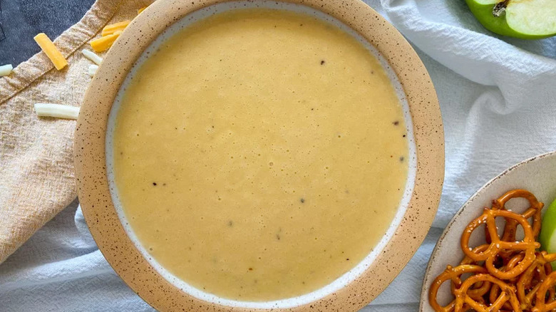 aerial shot of beer cheese sauce in a bowl with salty snack pretzels to the side