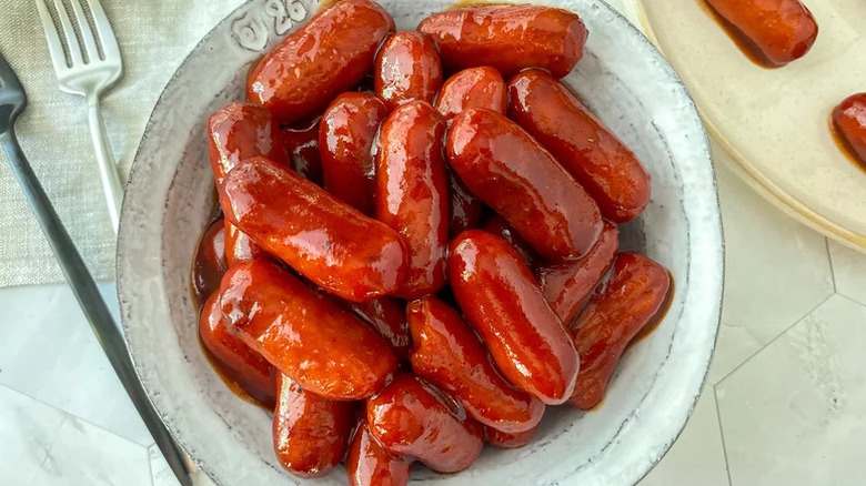 Pile of easy slow cooked little smokies in a bowl next to forks