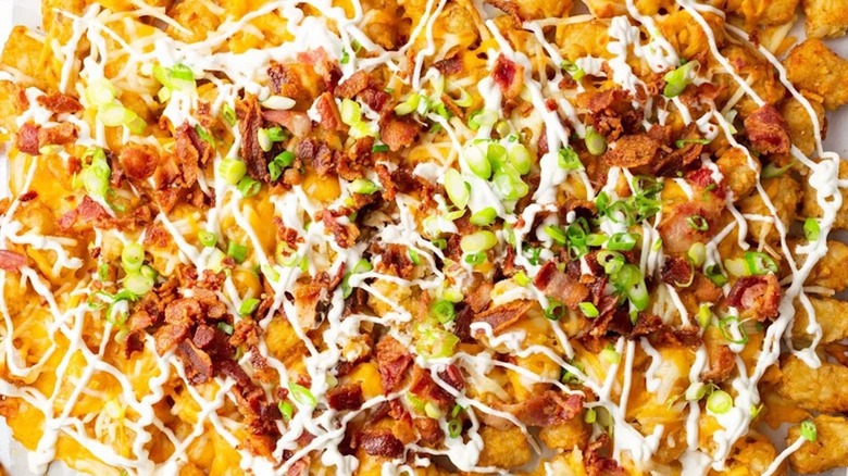 close up aerial view of loaded baked potato totchos, with tater tots smothered in bacon bits, sour cream, and green onion