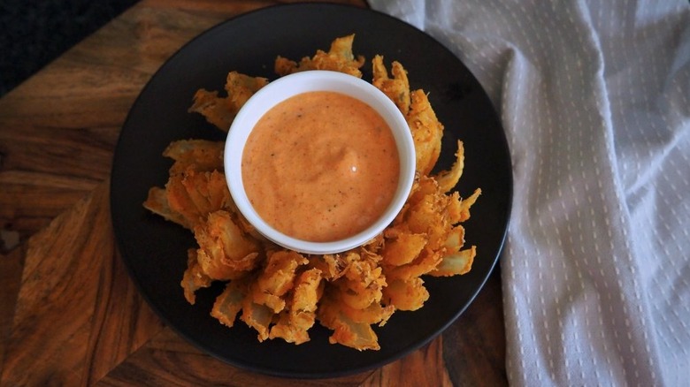 Aerial shot of the copycat Outback Bloomin' Onion fried onion crisps on plate with a bowl of dipping sauce in the middle