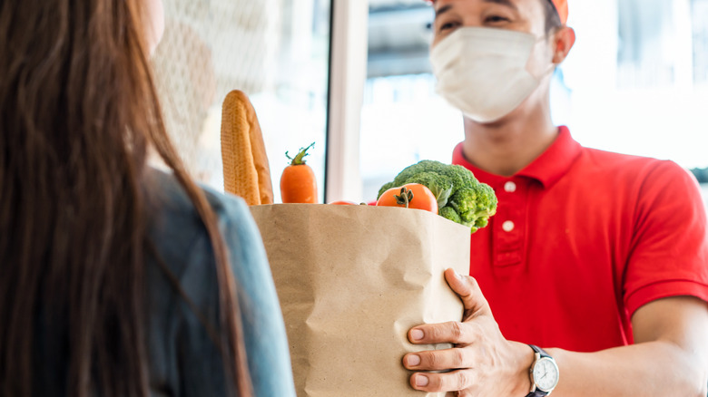 Grocery store employee handing customer bag of groceries