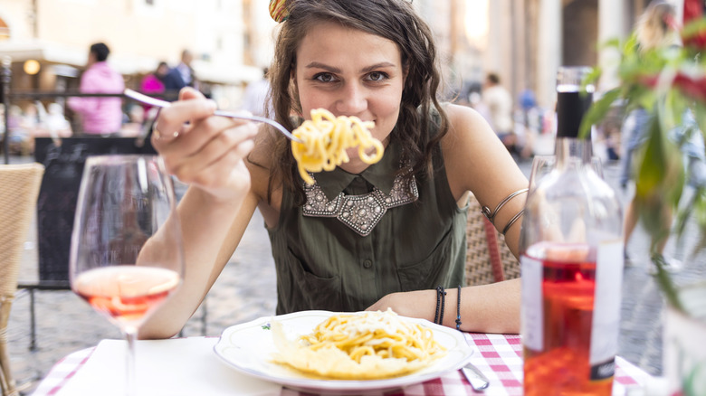 woman with pasta at restaurant patio table