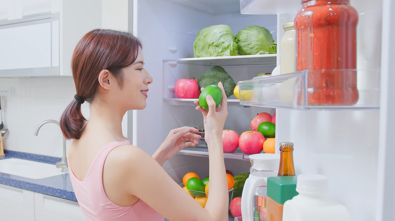 woman getting produce from refrigerator