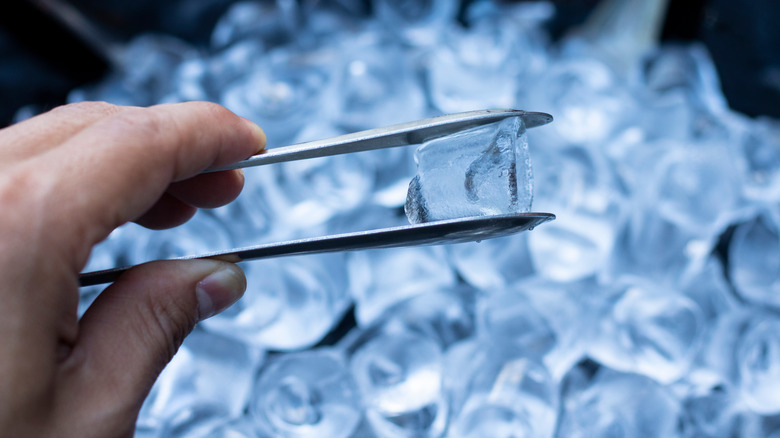 ice cubes and hand with tongs