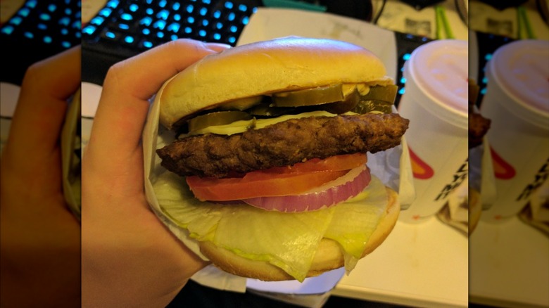 Hand holding a Carls Jr single cheeseburger