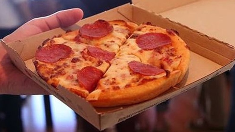 Hand holding a Pizza Hut pepperoni personal pan pizza