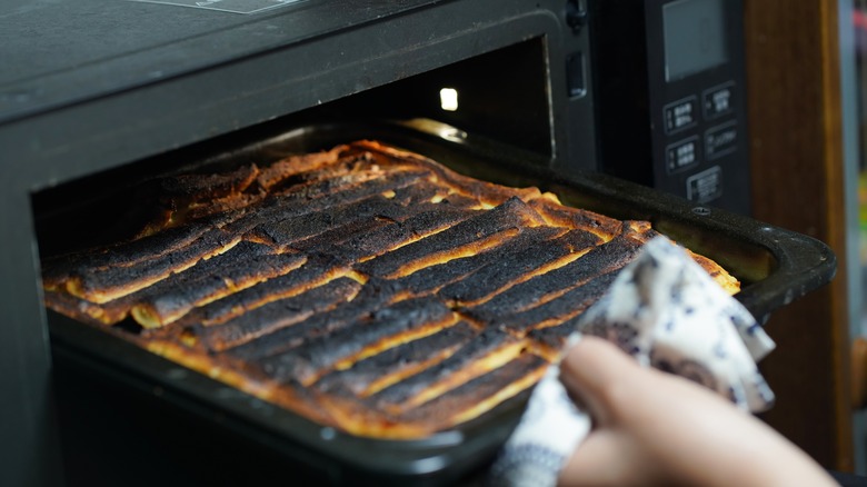 pulling burnt food from oven