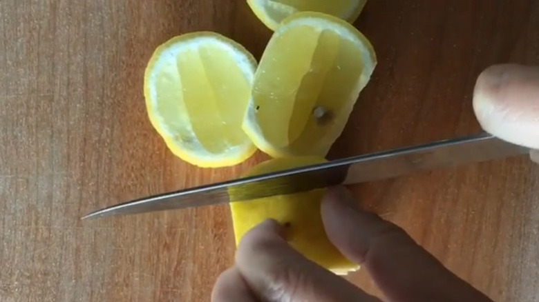 knife cutting lemon on board