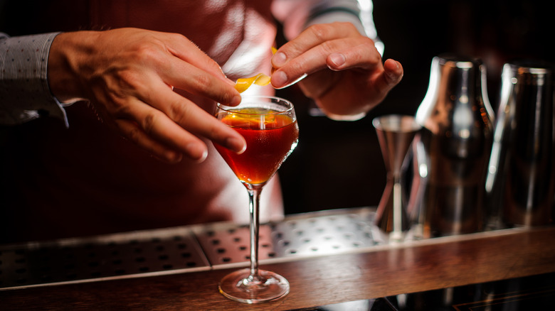 twisting lemon peel over cocktail