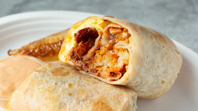 A breakfast burrito cut in half with the cross-section facing up