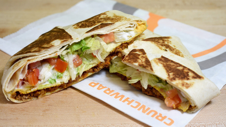 A Taco Bell crunchwrap sliced in half and placed on top of a Taco Bell paper bag