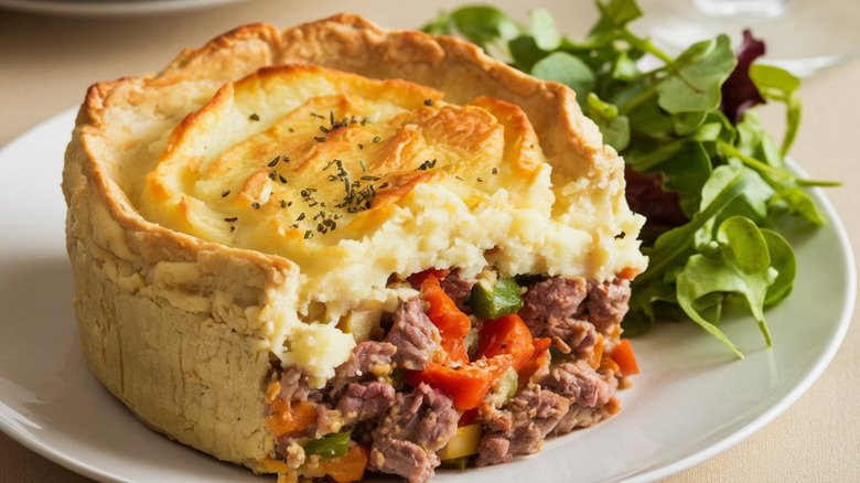 Sliced shepherd's pie and green salad on a white plate