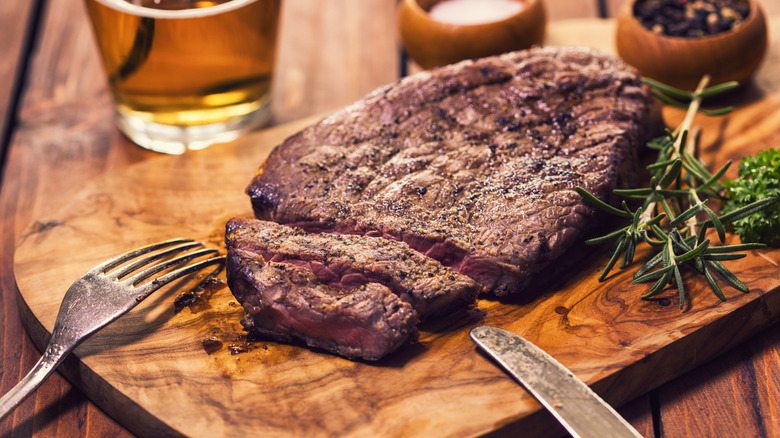 A large steak, fork, and knife on a serving board
