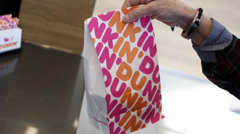 person holds bag of Dunkin' Donuts