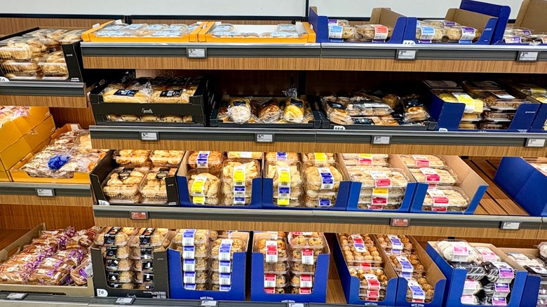 A variety of pastries in plastic clamshell containers on the shelves of an Aldi